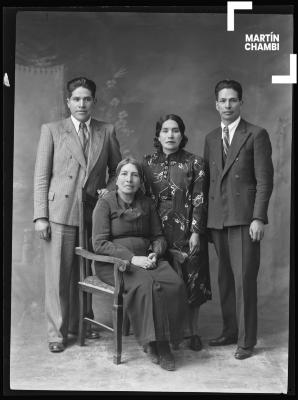 Retrato de mujer no identificada  junto a sus tres hijos en estudio fotográfico